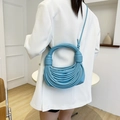 Blue PU leather crossbody bag with knot woven design worn by model in white suit - Blue