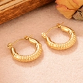 Détail de boucles d'oreilles créoles dorées texture bambou sur fond en feutre beige - Style Circulaire Bambou (WGXA03505509A)