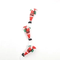 Dettaglio di tre pupazzi di Babbo Natale in peluche che salgono su una corda bianca - 25cm Tre Persone Corda