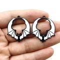 Detail of bat-shaped enamel charms in black and white shown on hand for size reference - Black & White
