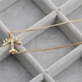 Collana a catenina dorata con ciondolo aereo in zirconi colorati su un portagioie grigio - Oro