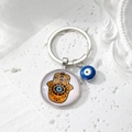 Macro shot of silver Hamsa Hand pendant with a blue Evil Eye charm on a key ring - 5# Yellow Brown Palm