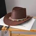 Brown straw cowboy hat with shell and bead decoration on a book for travel vibe - Reddish Brown