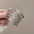 Close-up of a silver metallic hair claw with a unique twisted wire geometric design - Silver