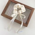Elegant cream bow hair scrunchie with long ribbon streamers in premium satin texture - White