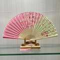Pink and green cherry blossom folding fan with wooden ribs and pink tassel on a stand - Flower Clusters (Pink)