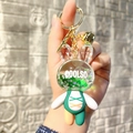 Detail of acrylic rabbit keychain featuring liquid quicksand, green outfit, and gold bell - Green