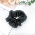Close-up of black satin scrunchie showing glossy texture and elegant soft fabric folds - Black