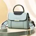 Chic mint green crossbody handbag with black trim and wide woven strap on geometric backdrop - Green