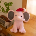 Pink plush elephant toy wearing a festive red Christmas hat with soft grey ears - Christmas Pink/Red Christmas Hat