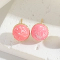 Macro shot of pink marble texture round stud earrings with golden metallic borders - Pink White