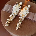Dettaglio di orecchini a fiori con nappe e perle su scatola regalo in velluto - Oro