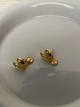 Detail of gold heart earrings with dangling coin charms on a minimalist ceramic plate - Gold