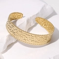 Detalle de brazalete de oro 18K con textura martillada y bordes perlados sobre piedra - Dorado