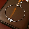 Detailed view of silver star bracelet with zircon inlay on brown jewelry box - Star Pendant Style / Silver