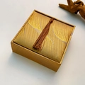 Top view of a square gold brocade jewelry box featuring a stylish brown tassel detail - Bracelet Box (Large Square)