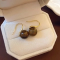 Close-up of golden earrings with oval tiger eye stones in a beige velvet jewelry box - Coffee Hook (10mm)