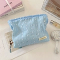 Close-up van lichtblauwe kanten make-uptas met zilveren lovertjes en een geweven label - Blauw