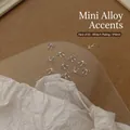 Detail of 20pcs 5x4mm silver alloy bowknot nail charms on a round display tray - XY-543 Mini Bowknot 5x4mm White K