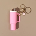Pink tumbler keychain with white straw and golden floral charm on a neutral surface - Pink