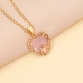 Fashion heart necklace with pink zircon pendant on gold chain over beige silk background - Pink