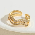 Macro-opname van de dubbellaagse golvende gouden ring met zirkonia en open verstelbaar design - Witte Zirconia Holle Stijl