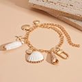 Vista macro de pulsera dorada marina con colgantes de conchas y estrellas de mar - Concha Dorada