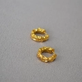 Dettaglio di orecchini a cerchio dorati con texture a lava e finitura martellata - Oro Piccolo