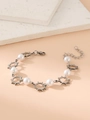 Close-up of silver stainless steel bracelet with sun charms and white pearls on beige surface - White Pearl Sun