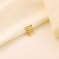 Détail d'un pendentif lettre F dorée ajourée avec finition mate sur tissu satiné - Lettre évidée F