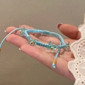 Gros plan d'un bracelet tressé bleu clair avec des breloques papillon et perles dorées - Style Papillon Tissé Bleu