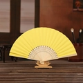 Yellow fabric folding fan with bamboo ribs on a wooden stand for DIY painting projects - Yellow