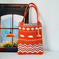 Close-up of orange knit tote bag featuring blue and white polar bear wave patterns - Bear Orange