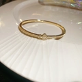 Macro shot of a gold clover charm bracelet with sparkling zircons on a white plate - 3# Golden Clover