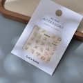 Macro shot of 12 zodiac gold nail charms and pearls on white accessory card - MJ-069 Pearl Style Silver Stamping / Silver