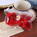Détail d'élastiques en peluche rouge dans un emballage transparent sur table en bois - Boule de Peluche Rouge Vif Lot de 20