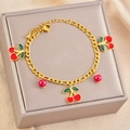 Elegante bracciale dorato con ciliegie rosse e foglie verdi su scatola regalo - Bracciale