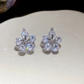 Macro shot of silver flower earrings featuring sparkling zircons with a starburst effect - Ear Buckle / White