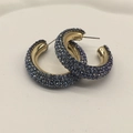 Detailed macro view of C-shaped hoop earrings featuring dense dark blue rhinestones - Blue