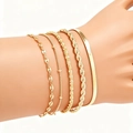 Close-up of stacked bohemian gold plated figaro chains and bangles on a wrist - SL189 Gold