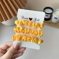 Three-piece set of bright yellow satin scrunchies on a Sweet Girl display card - 3 Piece Set / Goose Yellow