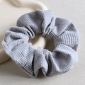 Dettaglio di un elastico in tessuto a nido d'ape azzurro su un vassoio beige elegante - Azzurro