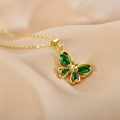Primer plano del collar mariposa dorado con alas de piedra verde sobre seda beige - Verde