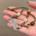 Détail d'un bracelet tressé vert avec un pendentif en forme de fleur de lotus blanc - Style Lotus Tissé Vert Armée