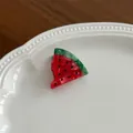 Macro shot of watermelon hair clip with red and green acetate texture on white plate - Watermelon