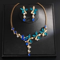 Elegante set di gioielli floreali dorati con cristalli blu su supporto nero - Oro-Blu