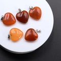 Five heart-shaped orange agate pendants with metal clasps displayed on a white stand - Red Agate