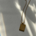 Macro view of gold rectangular pendant engraved with Love Each Other More text on bead chain - LOVE EACH OTHER MORE / Gold