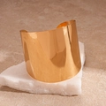 Polished gold wide geometric cuff bracelet displayed on a natural marble block - Gold