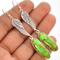 Detailed view of silver angel wing earrings with green stone held in hand for scale - S669 Angel Wing Turquoise